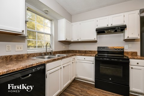 A kitchen with a black oven and white cabinets.