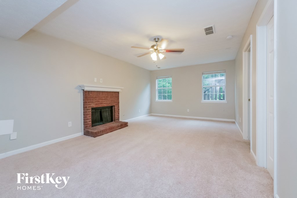A spacious room with a fireplace and a ceiling fan.