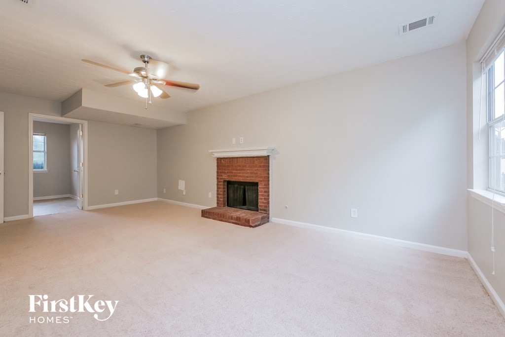 A spacious room with a fireplace and a ceiling fan.