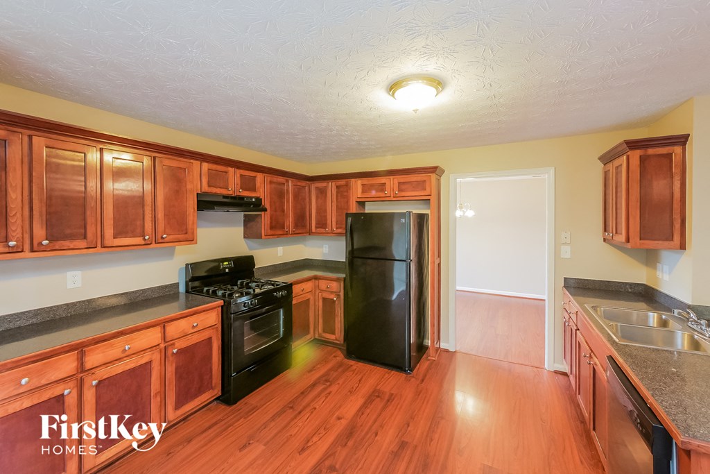 A kitchen with wooden cabinets and a black refrigerator.
