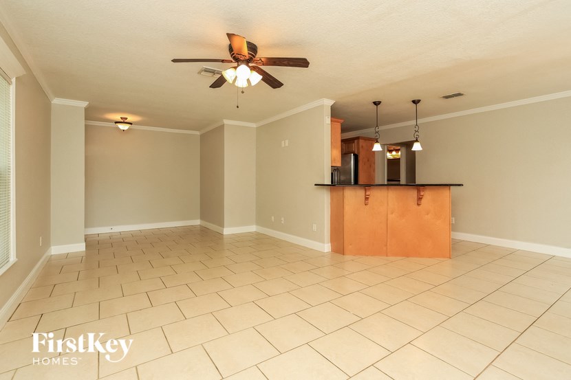 A spacious room with a ceiling fan and a bar area.