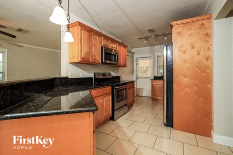 A kitchen with a black counter top and orange cabinets.