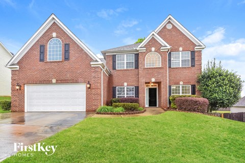 A brick house with a garage door and a green lawn.