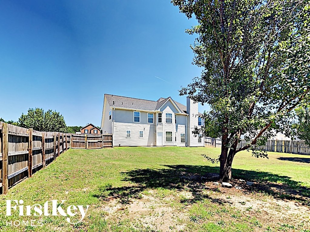 the backyard of a house with a fence and a tree