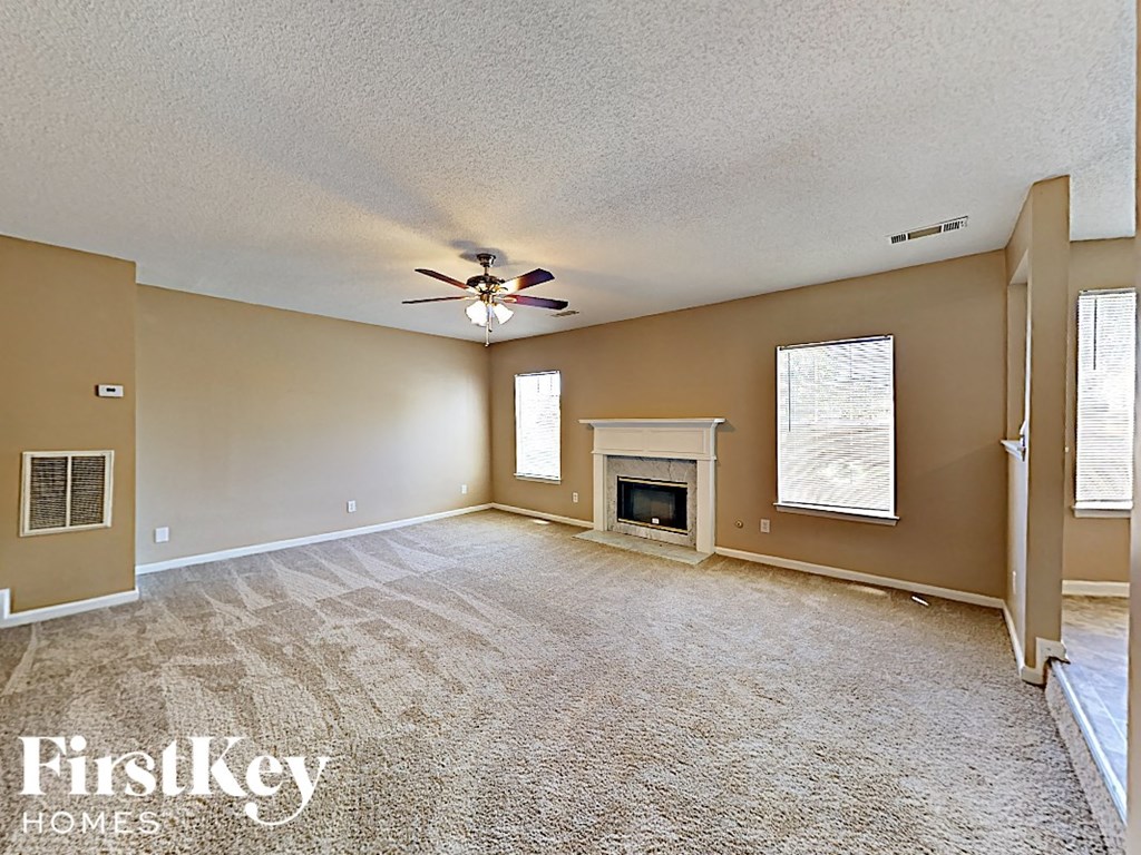 an empty living room with a ceiling fan and a fireplace