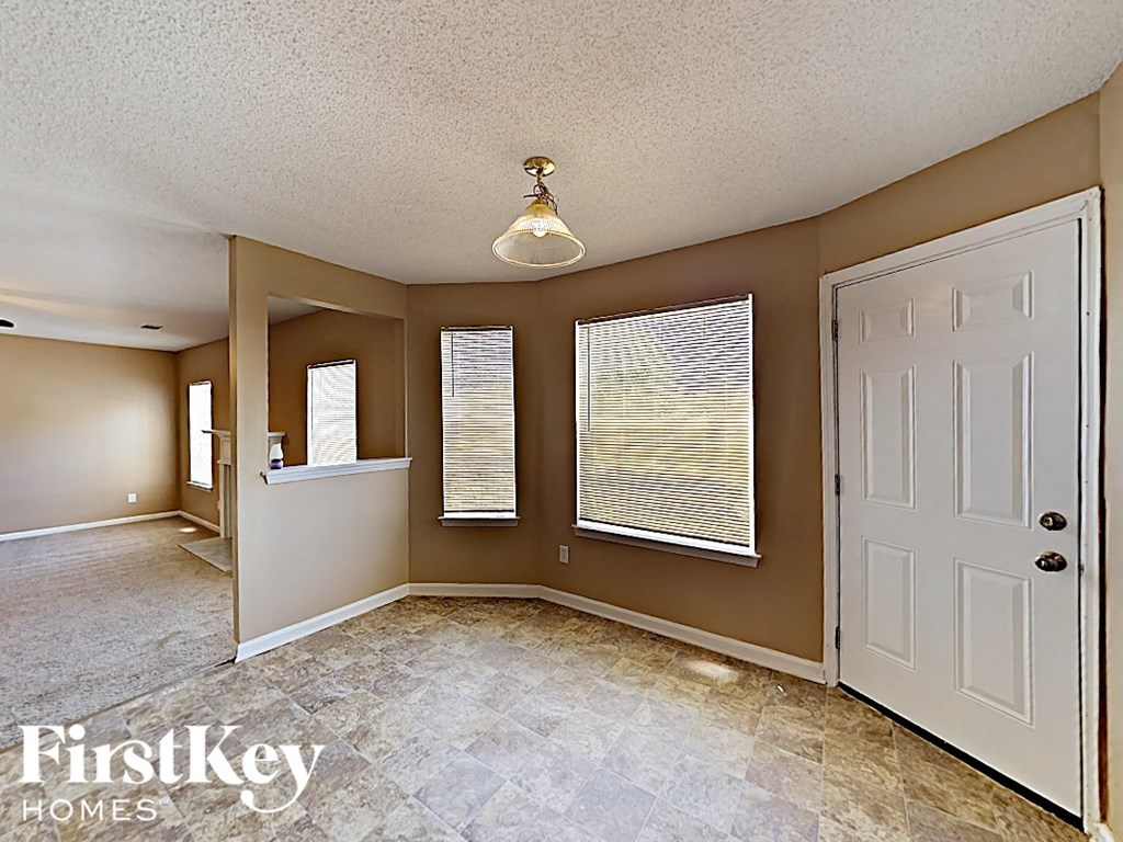 an empty room with a white door and three windows
