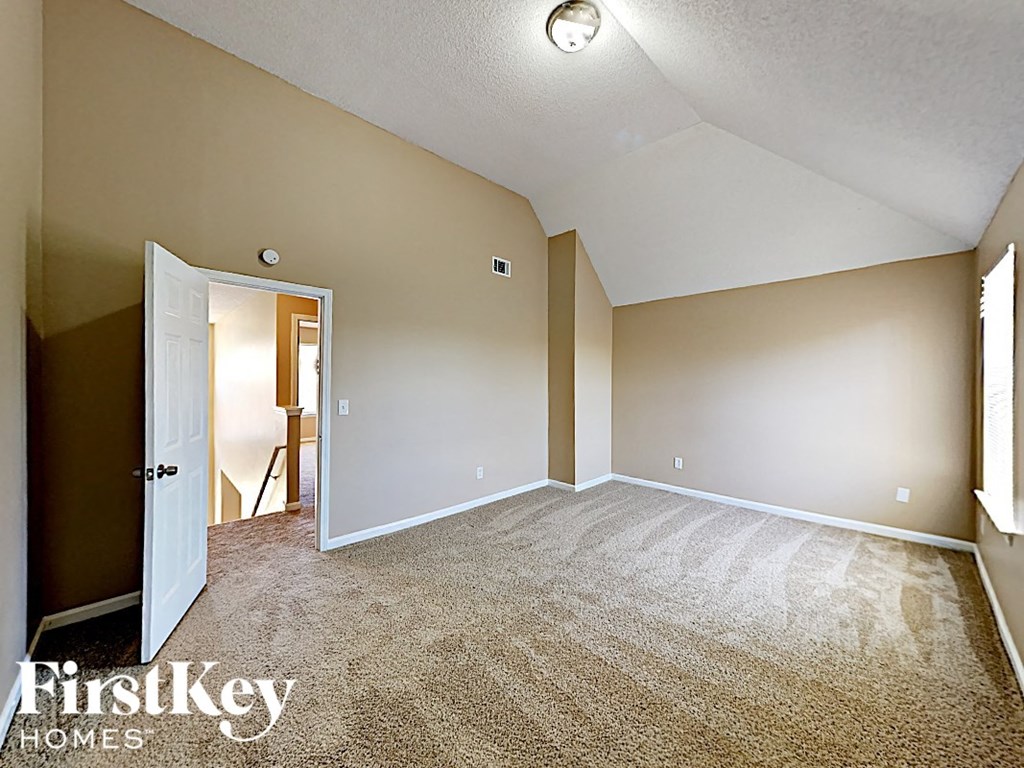 an empty living room with carpet and a door to a hallway