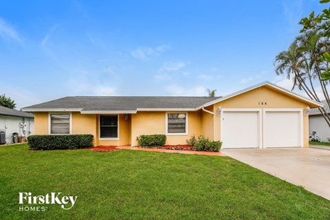 A yellow house with a grey roof and a white garage door.