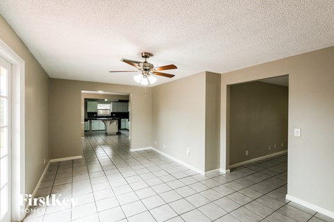 A spacious room with a fan and tiled flooring.
