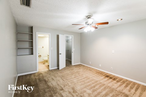 A room with a carpeted floor and a ceiling fan.