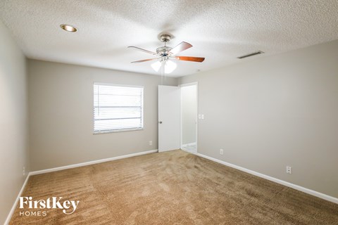 A room with a carpeted floor and a ceiling fan.