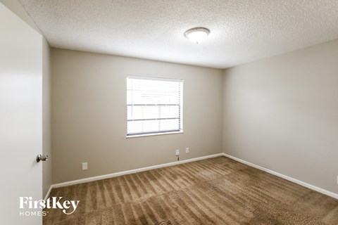 A room with a carpeted floor and a window with blinds.