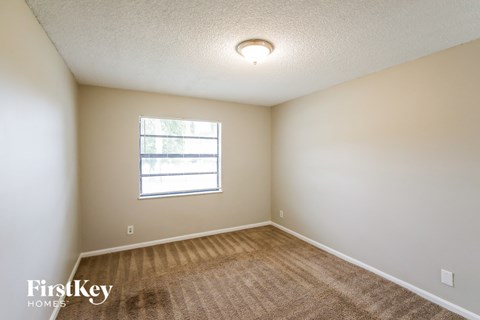 A room with a window and a carpeted floor.