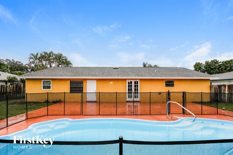 A yellow house with a pool in the backyard.
