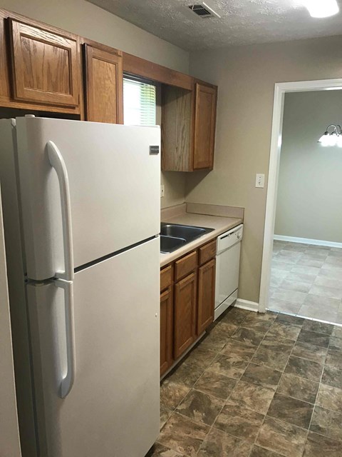 A kitchen with a white refrigerator and wooden cabinets.