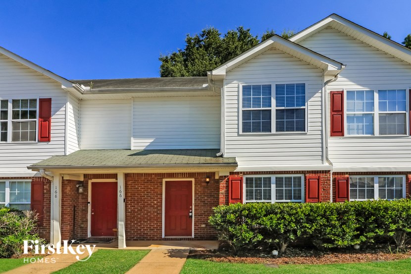 A white house with red doors and windows is for sale.