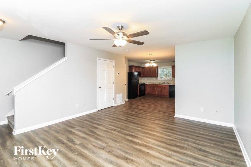 A spacious room with wooden flooring and a ceiling fan.