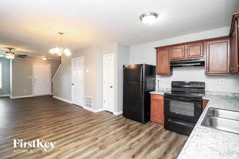 A kitchen with wooden cabinets and a black fridge.