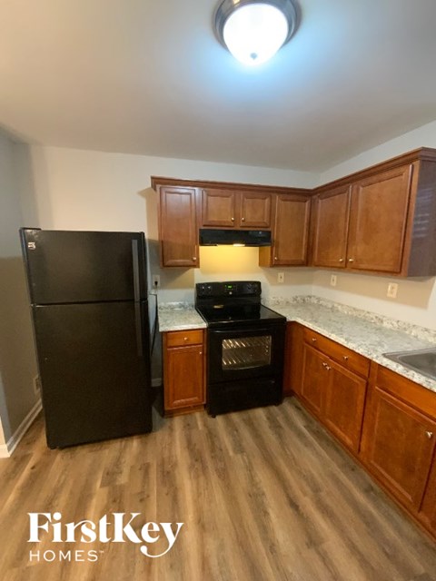 A kitchen with wooden cabinets and a black fridge.