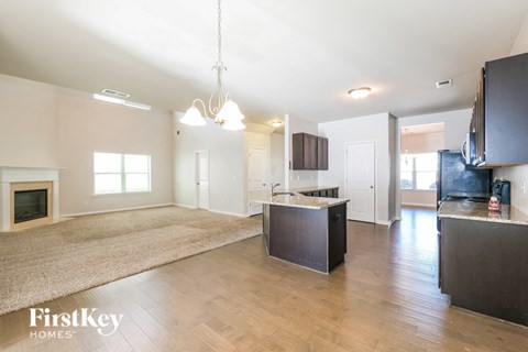 A spacious kitchen and living room with a fireplace and a rug on the floor.