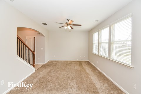 A spacious room with a carpeted floor and a ceiling fan.
