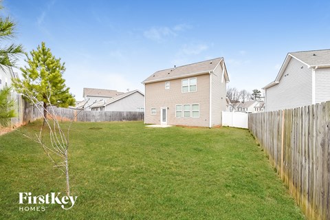 A grassy yard with a fence and a house in the background.