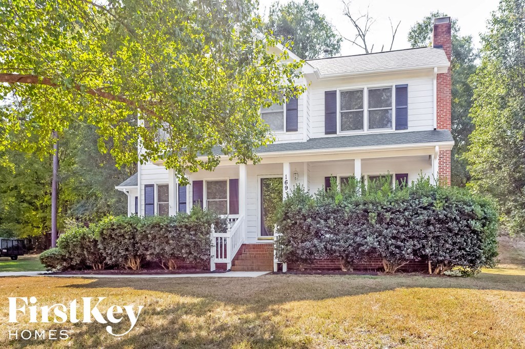 a white house with a lawn and a tree