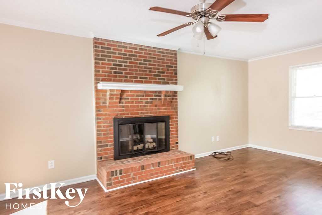 a living room with a brick fireplace and a ceiling fan
