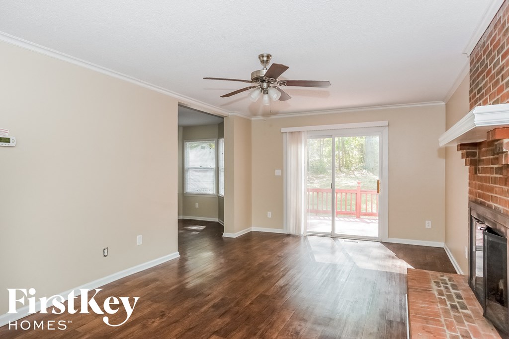 a living room with a brick fireplace and a ceiling fan