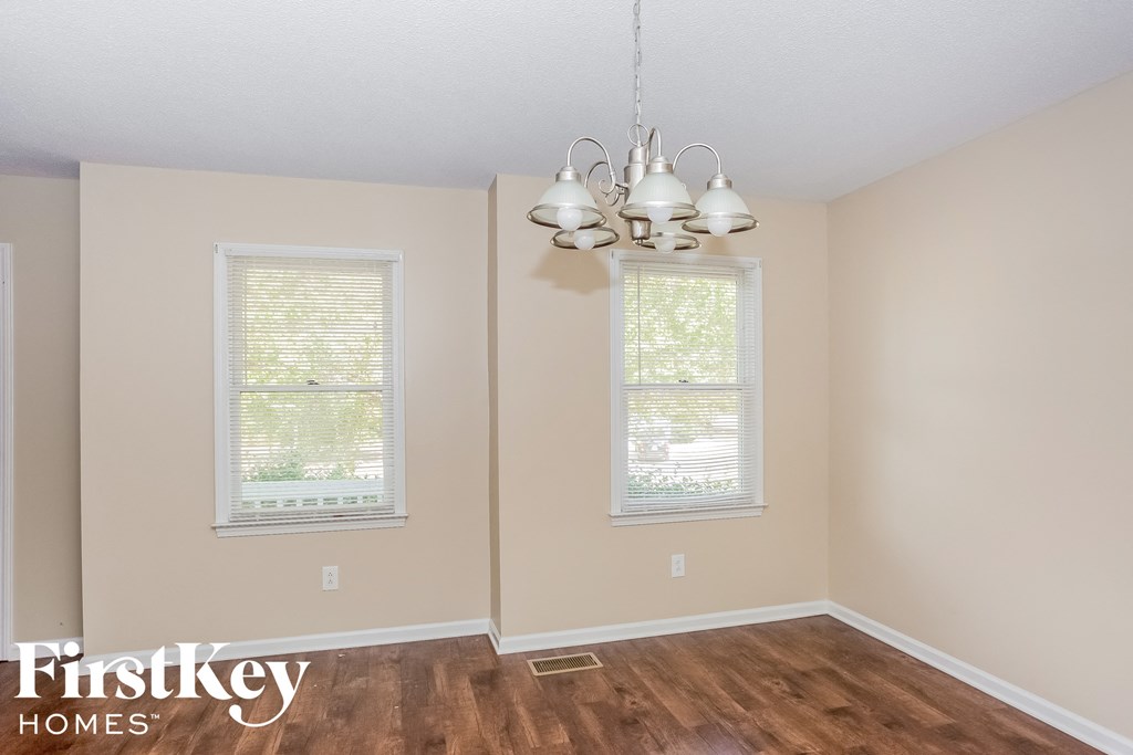 a bedroom with a wood floor and a chandelier and two windows