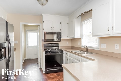 a white kitchen with black appliances and white cabinets