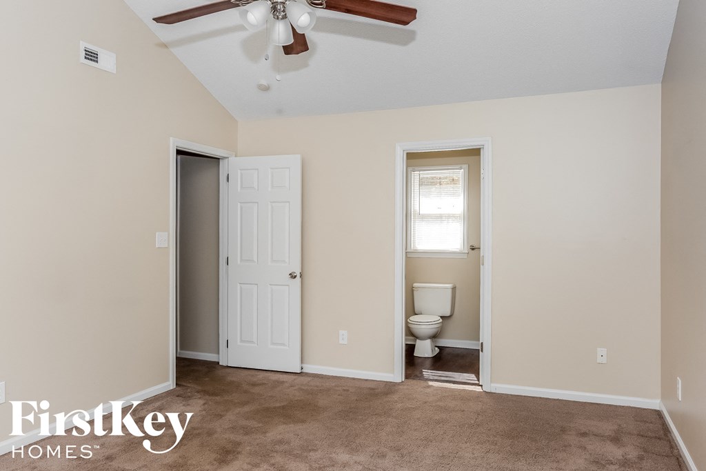 a room with a toilet and a closet and a ceiling fan