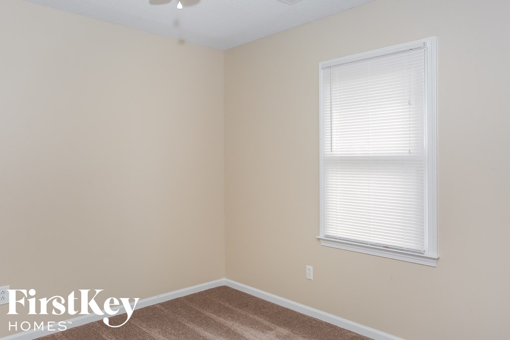 a small bedroom with a window and a carpeted floor