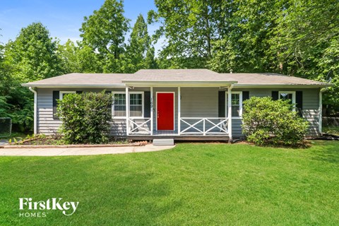 A house with a red door and a green lawn in front.