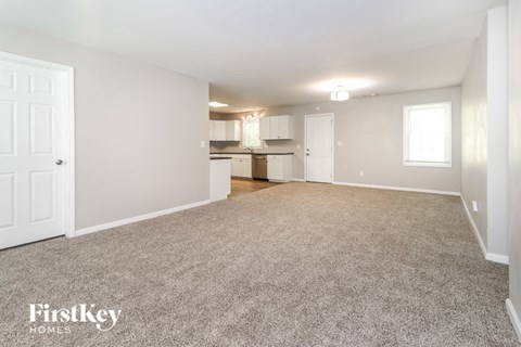 A spacious empty room with a carpeted floor and white walls.