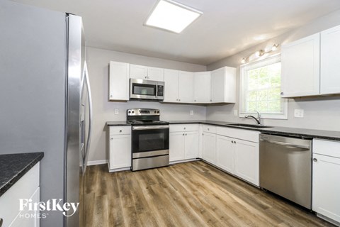 A kitchen with white cabinets and a stainless steel refrigerator.
