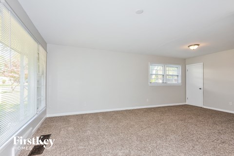 a spacious living room with white walls and a large window
