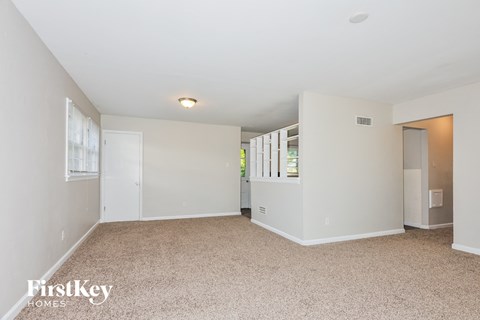 a spacious living room with white walls and a carpeted floor