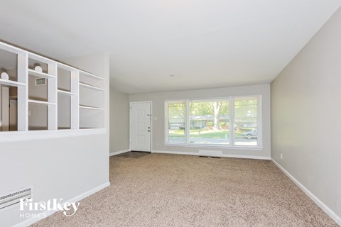 a living room with a large window and white shelves