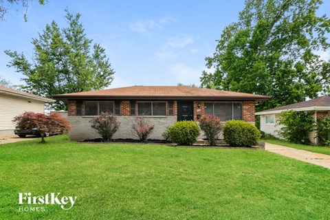 a small brick house with a lawn in front of it