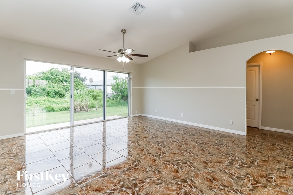 an empty living room with a sliding glass door and a ceiling fan