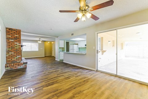 A spacious living room with a brick fireplace and wooden floors.