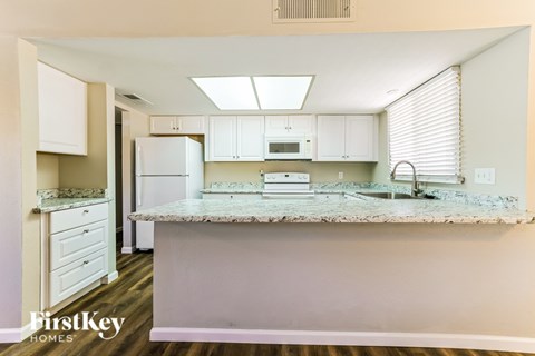 A kitchen with a white fridge, microwave, and cabinets.