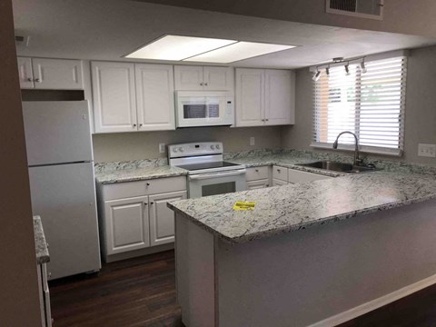 A kitchen with white cabinets and a granite countertop.