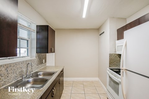 A kitchen with a sink, stove, and refrigerator.