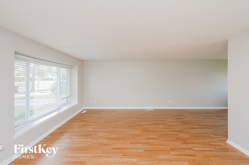 an empty living room with wood floors and a large window
