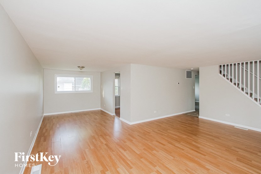 the living room and dining room with wood floors and white walls