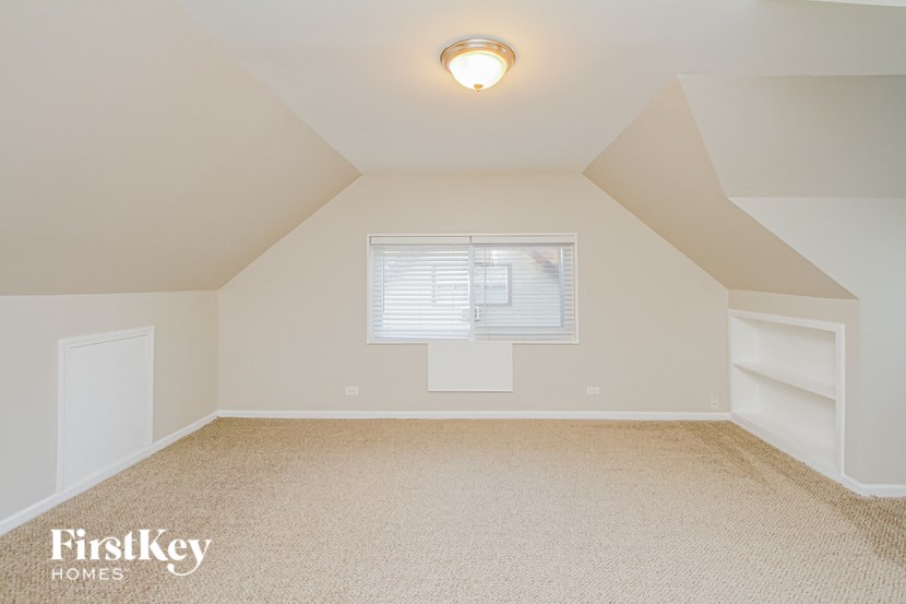 the attic bedroom of a home with a window and white shelves