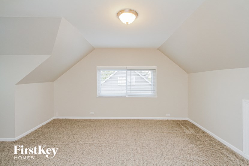 the attic bedroom of a home with a window and a ceiling fan