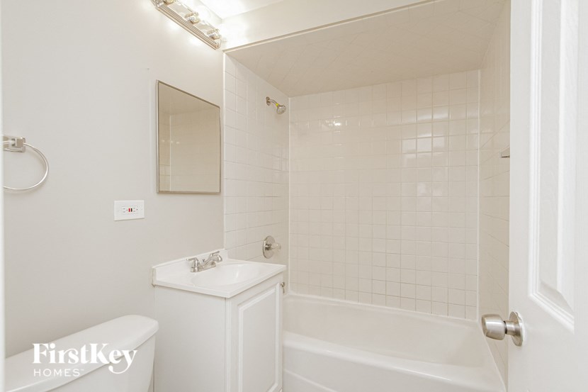 a white bathroom with a tub and a sink and a mirror